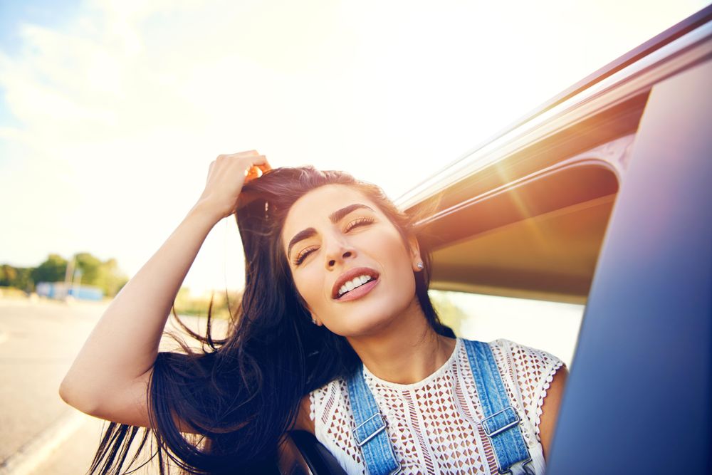 Happy female leaning while looking out of car window