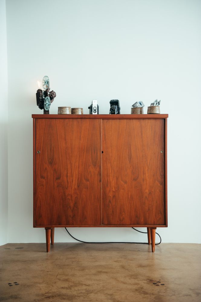 Mid-century modern bookcase with sliding doors and vintage cameras on top