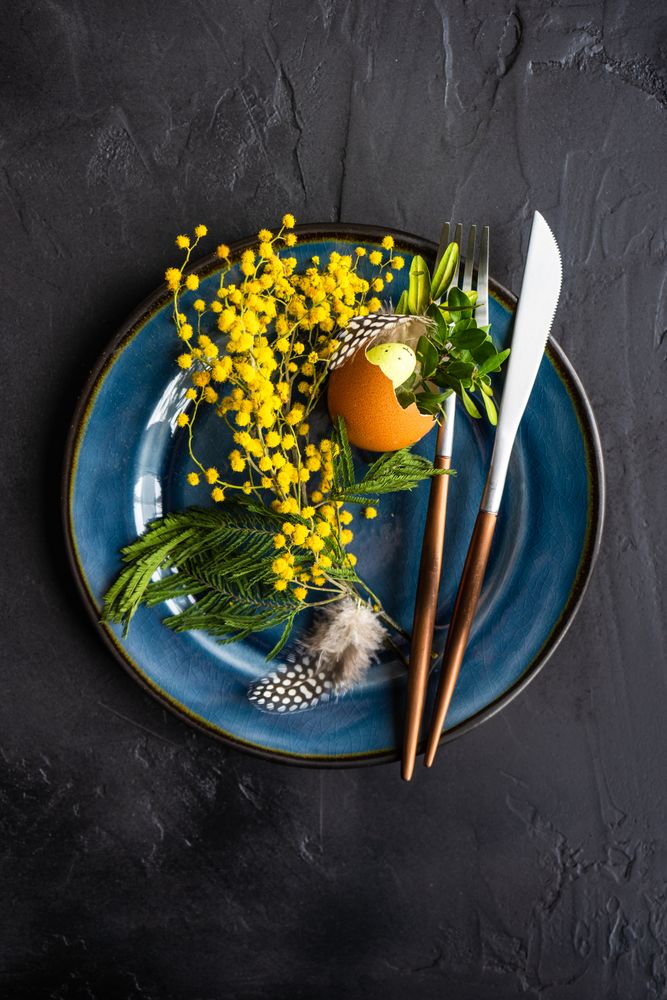 Top view of rustic table setting with decorate spring foliage on navy plate