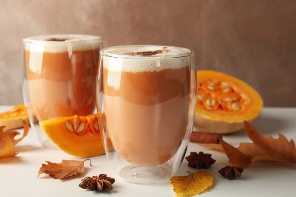 Composition with pumpkin latte, cinnamon, leaves and pumpkin on wooden table