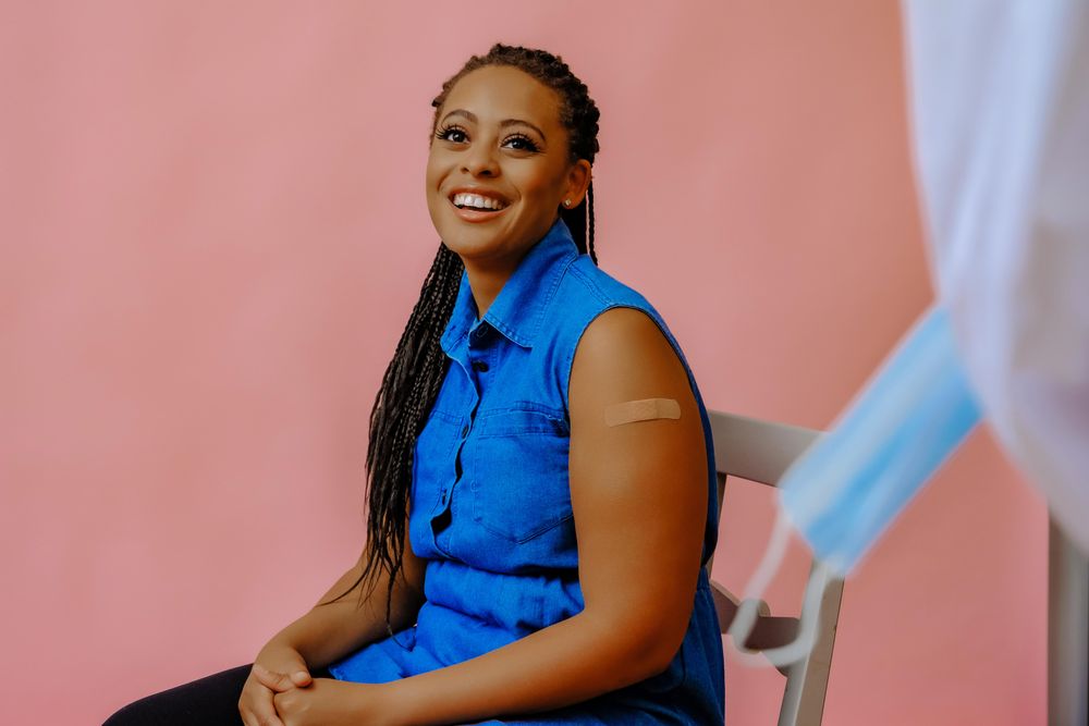 Smiling female patient with doctor or nurse after injection in studio shoot