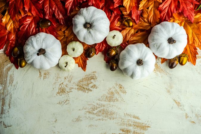Top view of autumn flatlay with light pumpkin ornaments and leaves with space for text