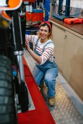 Portrait of mechanic woman repairing motorcycle on factory