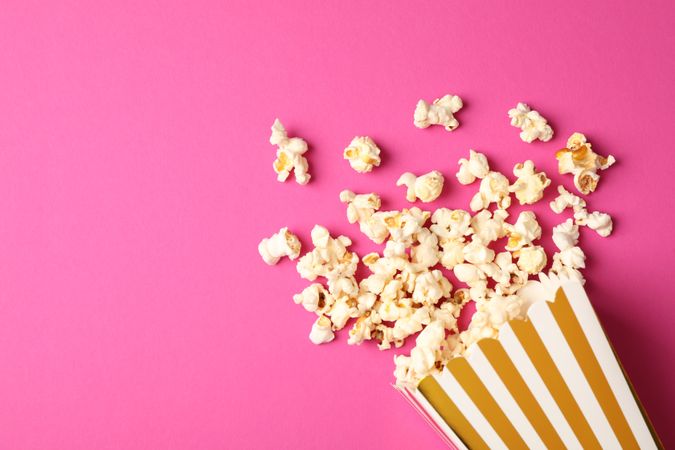 Flat lay composition with striped box and popcorn on color background