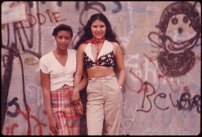 Two Latina woman pose in Front of a Wall of Graffiti in Lynch Park in Brooklyn, 1974