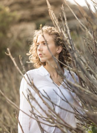 Young woman near dry twigs of bushes