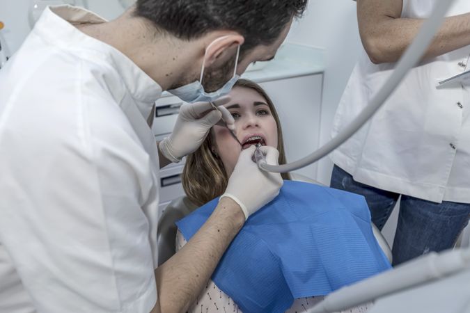 A portrait of a dentist examining female's mouth