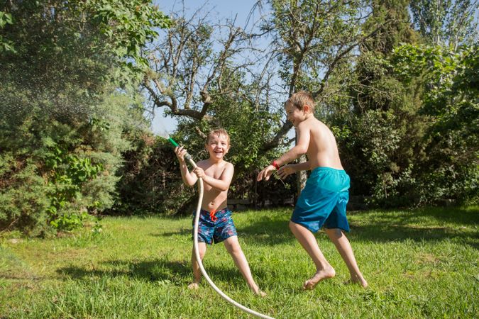 Little kids in swimwear having fun with splashing water