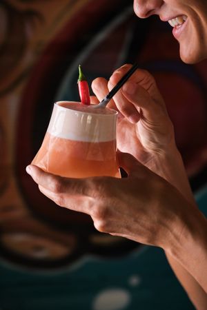 Crop female drinking cocktail using straw
