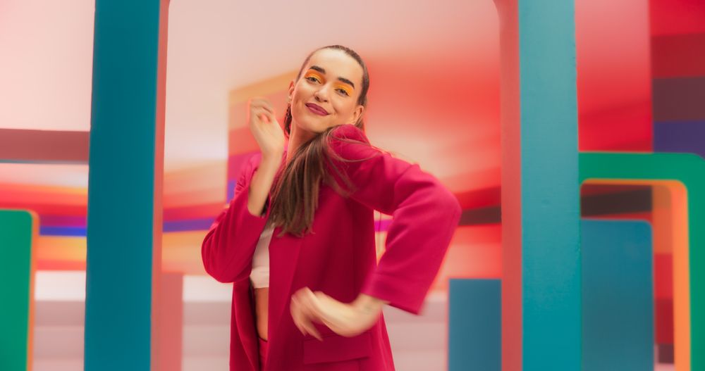 Portrait of Beautiful Young Woman Standing in Geometric Abstract Environment, Dancing with Hypnotic Graceful Movements. Fashionable Female Dancer in Colorful Studio Practicing Her Routine.