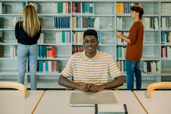 Happy young Black man sitting with closed laptop