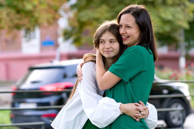 Mom and teenage daughter hugging on walk in park