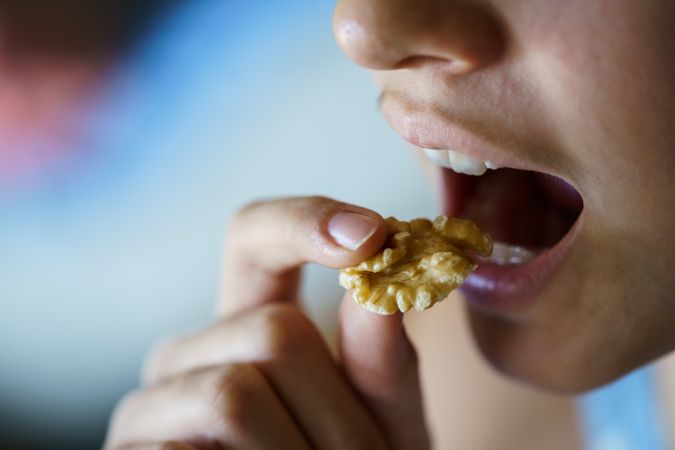 Crop of teenage female about to bite into a delicious walnut