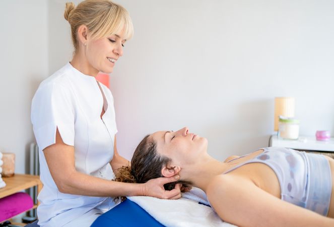 Physiotherapist massaging neck of client in clinic