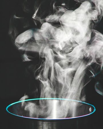 Water vapor coming out of a pot in a dark room