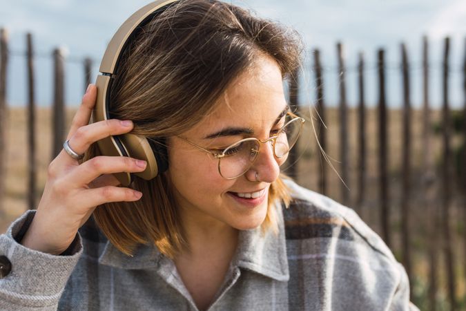 Happy young person listening to music in headphones in countryside