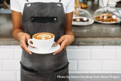 Barista in apron holding large cappuccino 4jxqR0