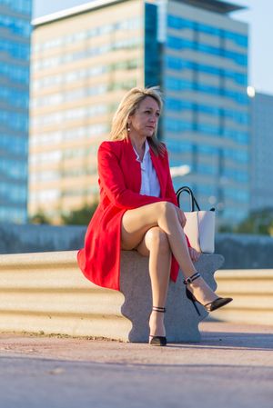 Blonde woman sitting on a bench and looking in the distance