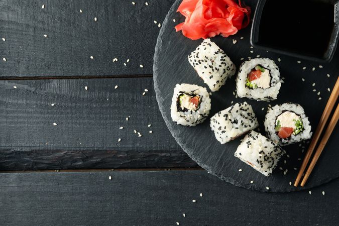 Tray with delicious sushi rolls on wooden background, top view. Japanese food