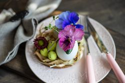 Easter table setting with elegant pink plate, colorful flowers and decorative eggs