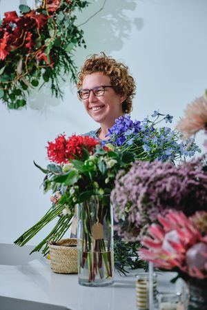 Smiling female florist with various flowers at counter