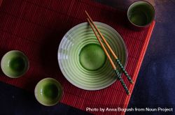 Green bowl with chopsticks on red table setting bxAEAX