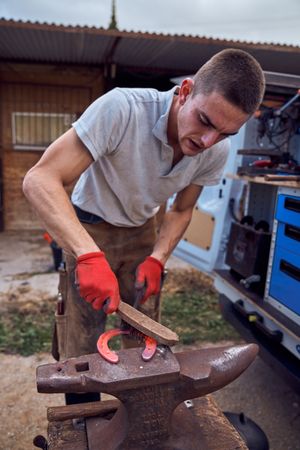 Blacksmith working on the anvil changing the horseshoe to a paw with tools
