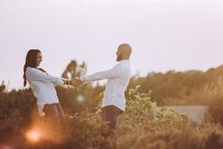 Romantic couple holding hands while standing at rural field