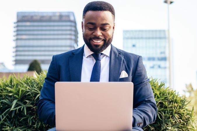 Business Black man in suit working with laptop outside