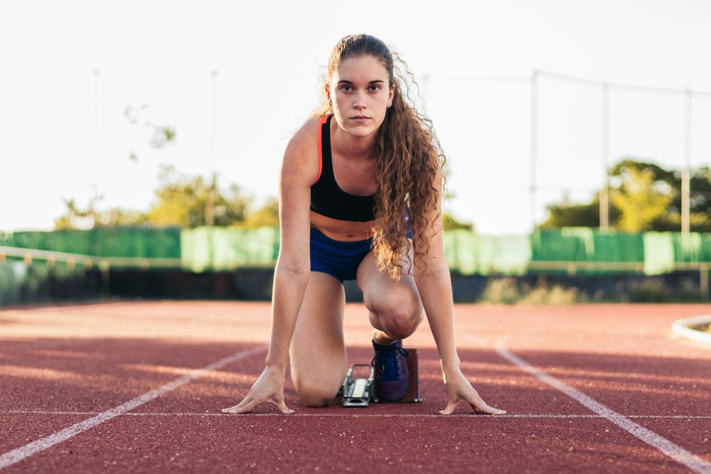 A female athlete getting ready to run on an athletics track.