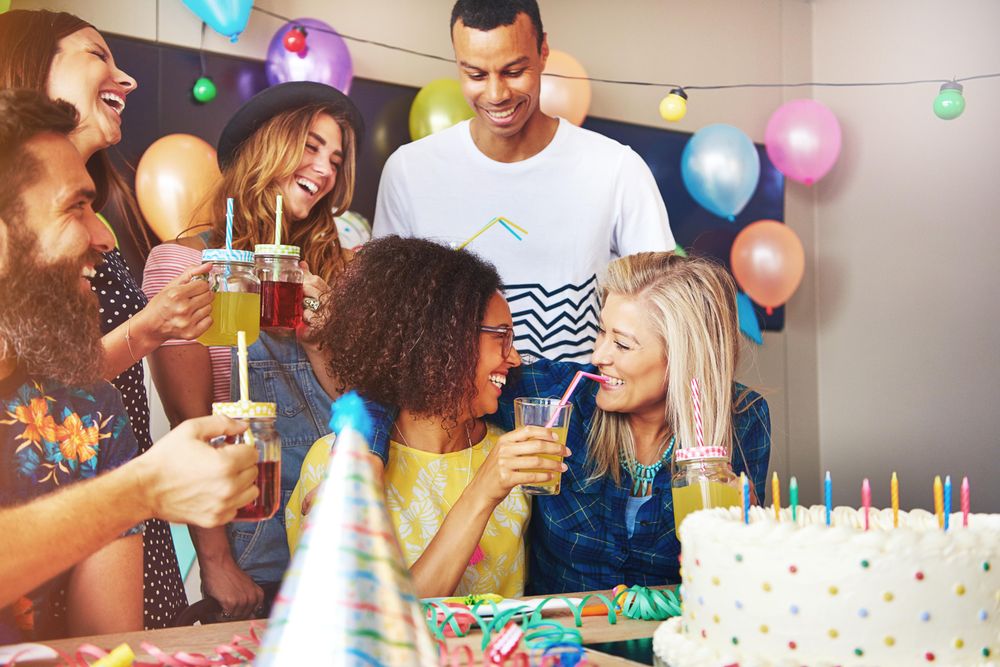 Woman celebrating her birthday giving friend a sip of juice at her party