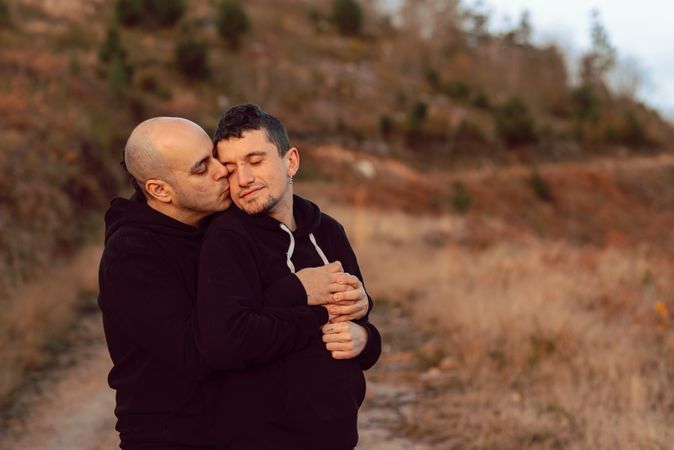 Men hugging on road on hill