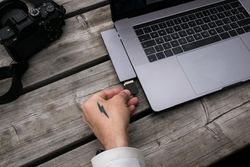 Male tattooed hands with camera and laptop