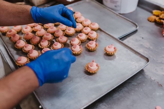 Anonymous baker decorating small cakes