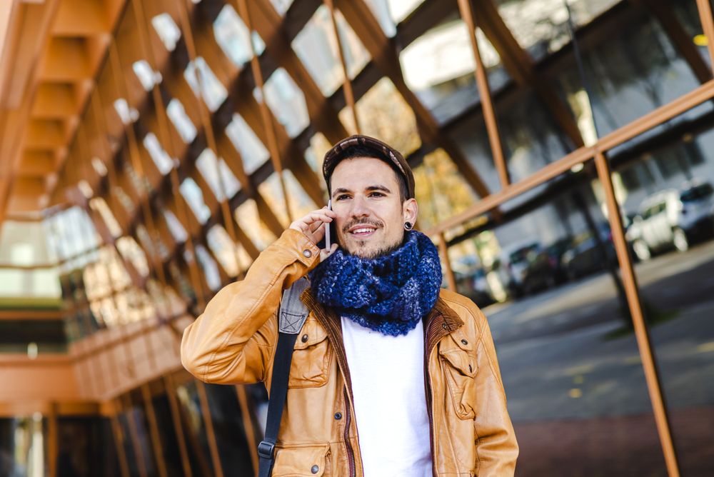 Stylish guy using smartphone outside modern building