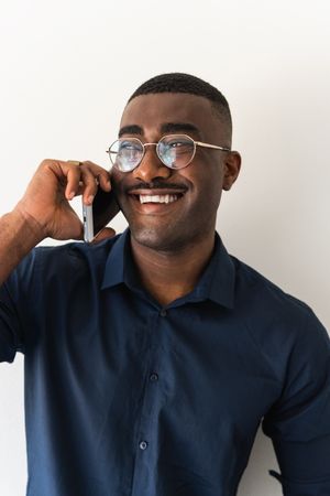 Black guy with phone near white wall