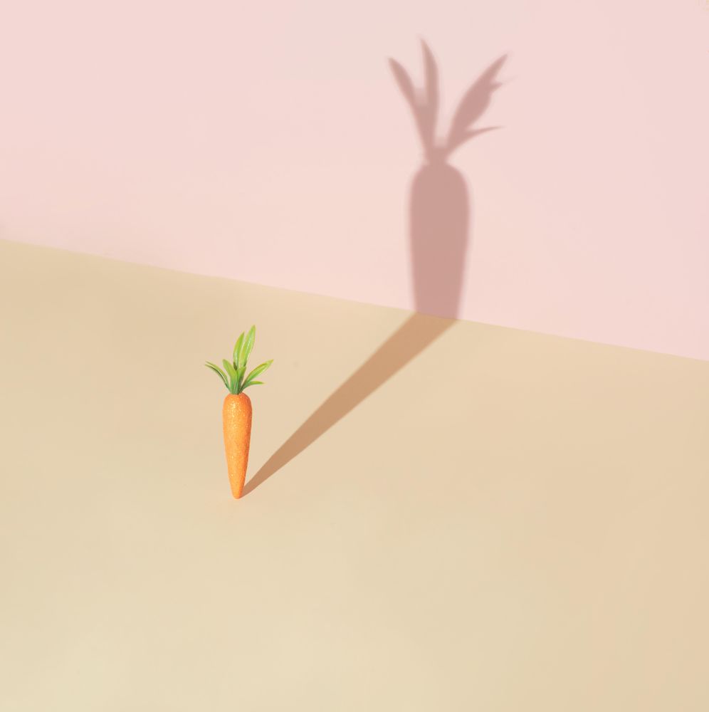 Carrot and shadow on pastel yellow background