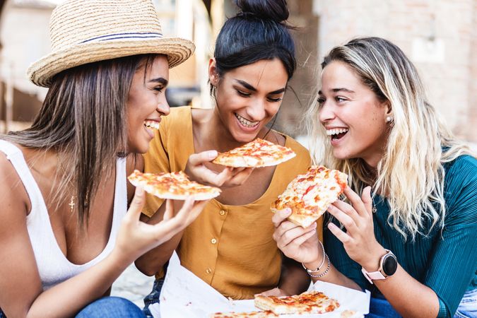 Diverse group of female friends enjoying take away pizza outside