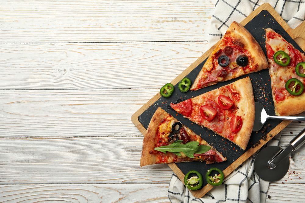 Board with tasty pizza slices on wooden background