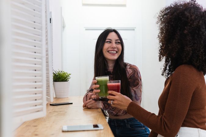Cheerful diverse women drinking smoothie in bar
