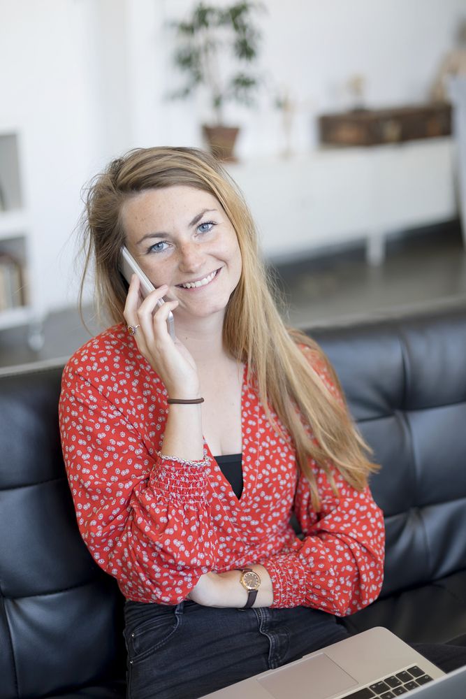 Happy woman talking on the phone sitting on a sofa in the living room at home