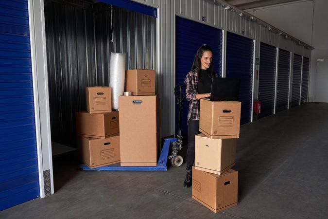 Woman browsing laptop near boxed in storage