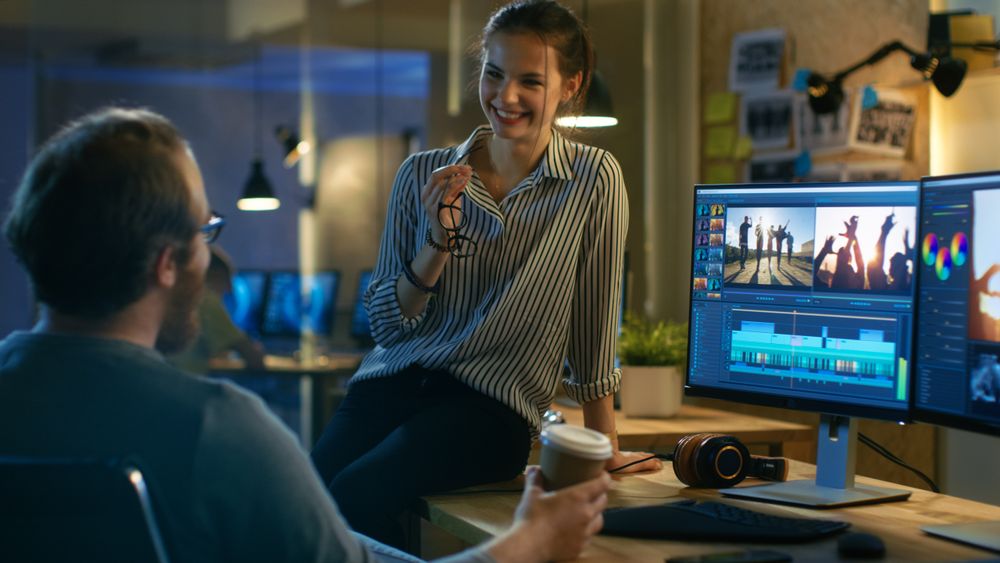 Female and Handsome Male Video Editors Discuss Footage They're Working On.