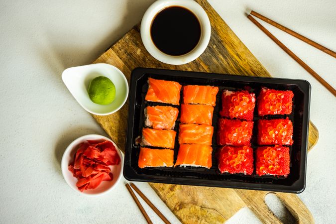 Top view of to go box of salmon & tuna sushi rolls