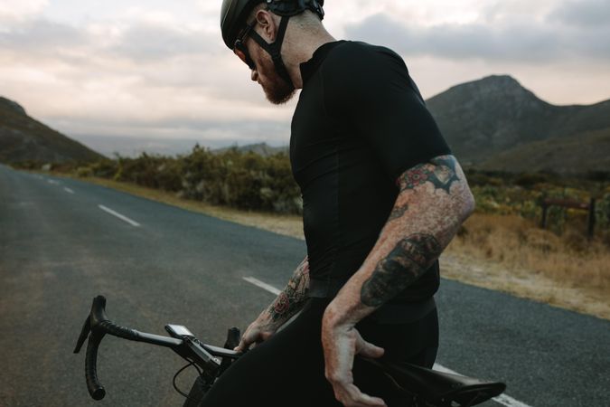 Tattooed cyclist looking at bike watch connected to handlebars