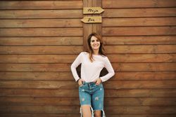Woman leaning on wooden wall with two signs