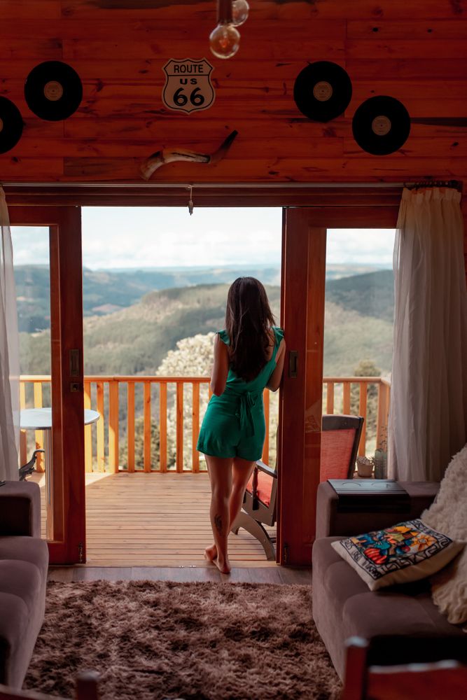 Back view of woman standing at the door of the balcony looking at the mountainous landscape