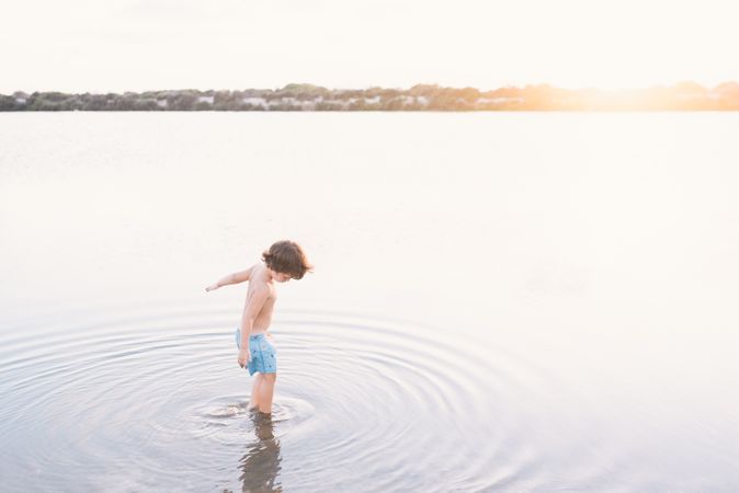 Boy walking in water of lake