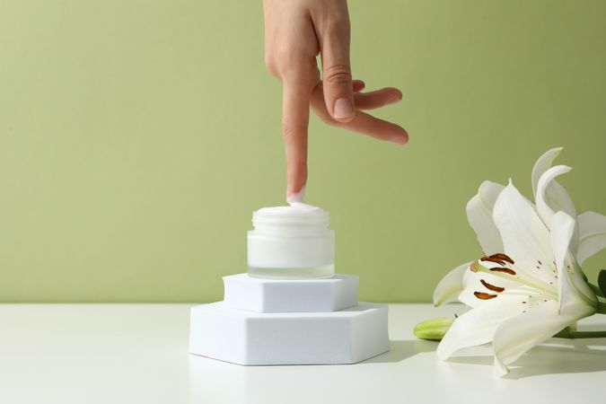 A jar of hand cream with flowers on a light background.