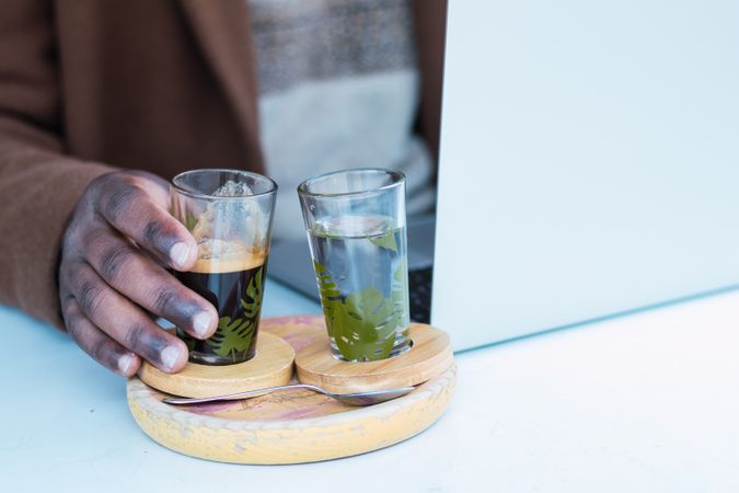 Crop Black man with espresso and glass of water in cafe